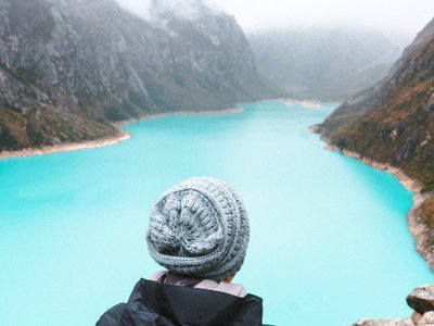 Frau schaut von oben auf einen türkisblauen See bei Huaraz