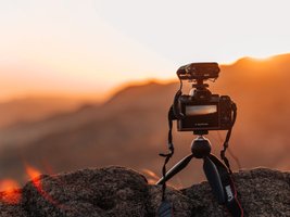 Kamera auf kleinem Stativ fotografiert einen Sonnenuntergang