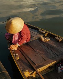 Frau kniet auf einem kleinen Holzboot im Licht der untergehenden Sonne