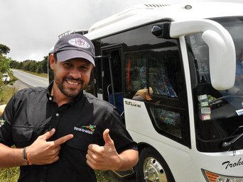 Reiseleiter Jonathan Serrano glücklich vor einem Reisebus