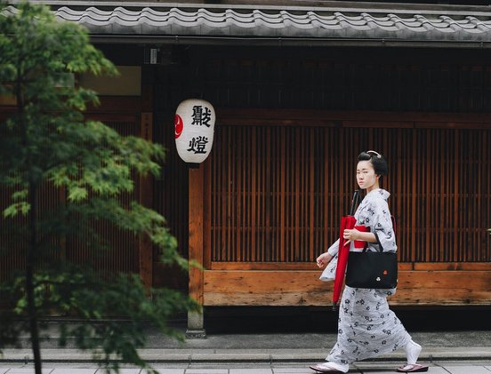 Japanisches Geisha läuft an Haus vorbei