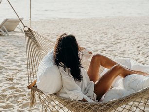 Frau in Hängematte entspannt am Strand