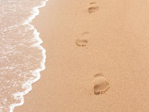 Fußspuren im Sand, bevor eine Welle kommt