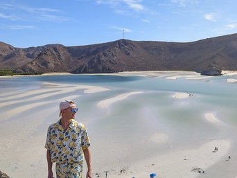 Ein Mann steht auf einer Anhöhe vor dem Playa Balandra und schaut in die Ferne