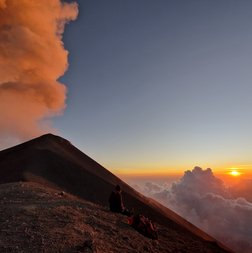 Ein Mann genießt den Sonnenuntergang am Volcán de Fuego