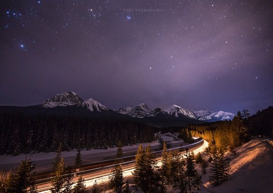 Sternenhimmel über der verschneiten landschaft und einer beleuchteten Straße