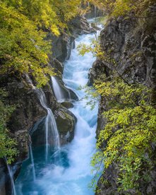 Tiefblaues Wasser der Soca fließt durch Felswände inmitten herbstlicher Bäume