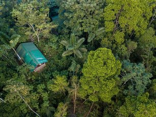 Drohnenaufnahme eines Hüttchens der La Tigra Rainforestlodge umgeben von Regenwald
