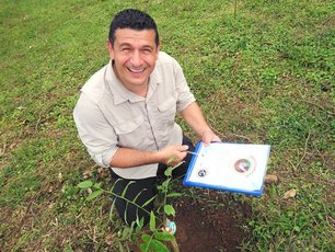 Adolfo pflanzt in La Tigra einen Baum und zeigt das Zertifikat dazu.