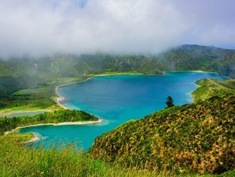 Türkisfarbener See in grüner Landschaft. Ein paar Wolken