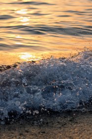 Welle bricht an Strand bei Sonnenuntergang