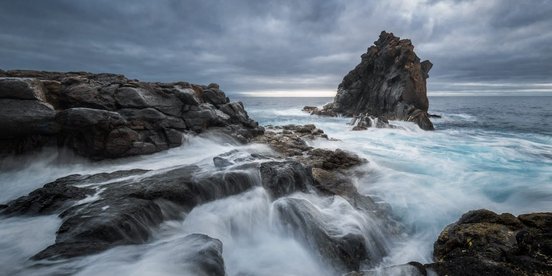 Langzeitbelichtung eines großen Felsens im Meer