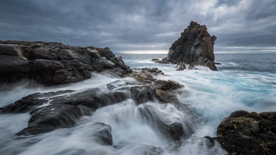 Langzeitbelichtung eines großen Felsens im Meer