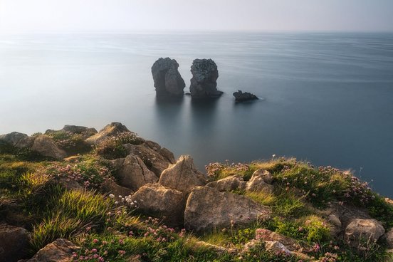 Aussicht von bewachsener Klippe auf Felsen die aus dem Meer ragen