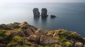 Aussicht von bewachsener Klippe auf Felsen die aus dem Meer ragen